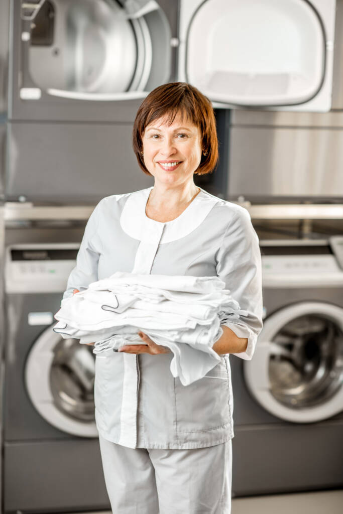 Employee from Tidy Loads Laundry with folded towels providing airbnb laundry service in Jacksonville, Nocatee, St. Johns